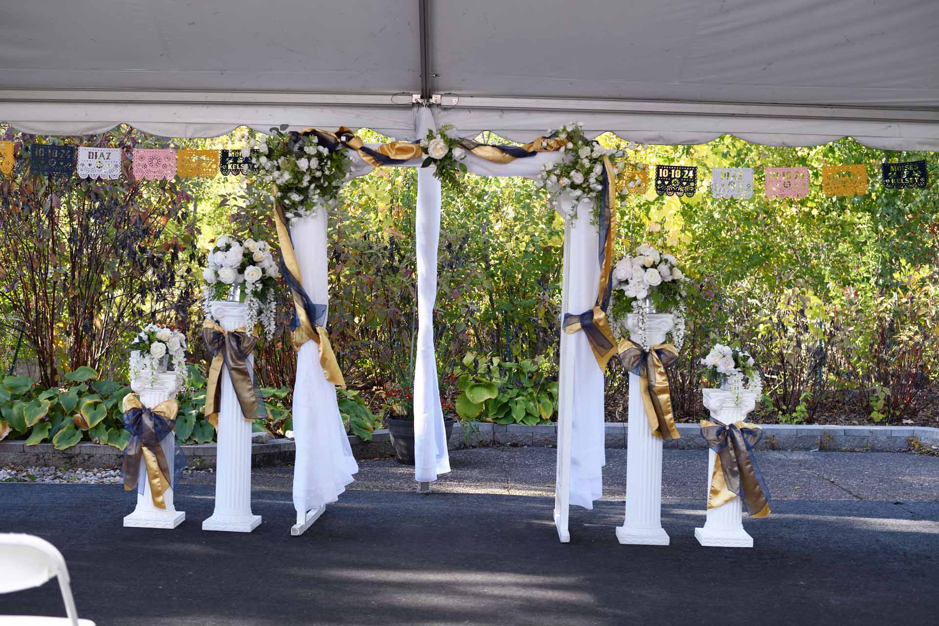 Wedding arch with floral decorations outside tent.
